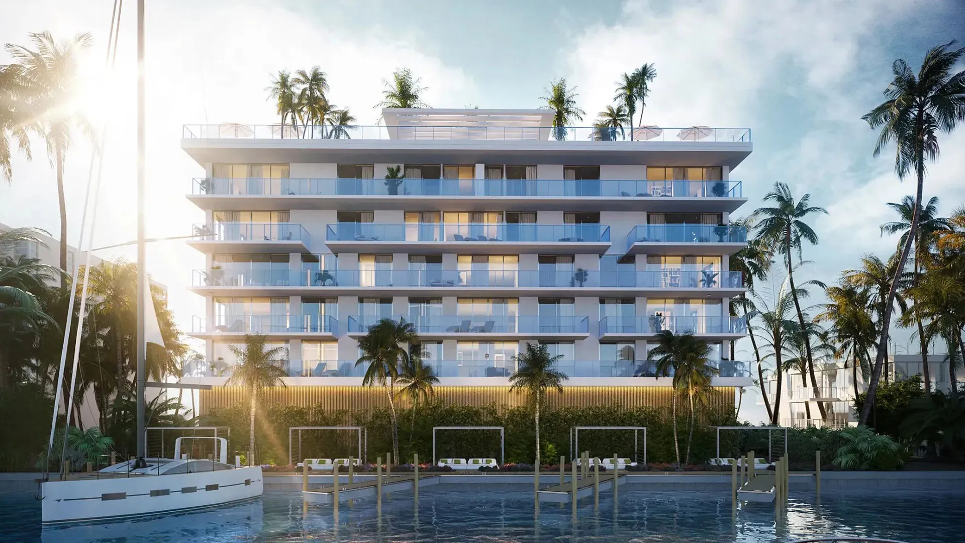 The Origin Residences facade seen from the water at dusk, its stepped balconies framed by palms above a private dock.